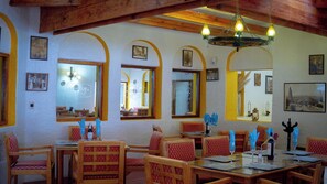 A restaurant interior with wooden beams, arched windows, and framed pictures on the walls. - Villas Arqueologicas Teotihuacan (Teotihuacan)