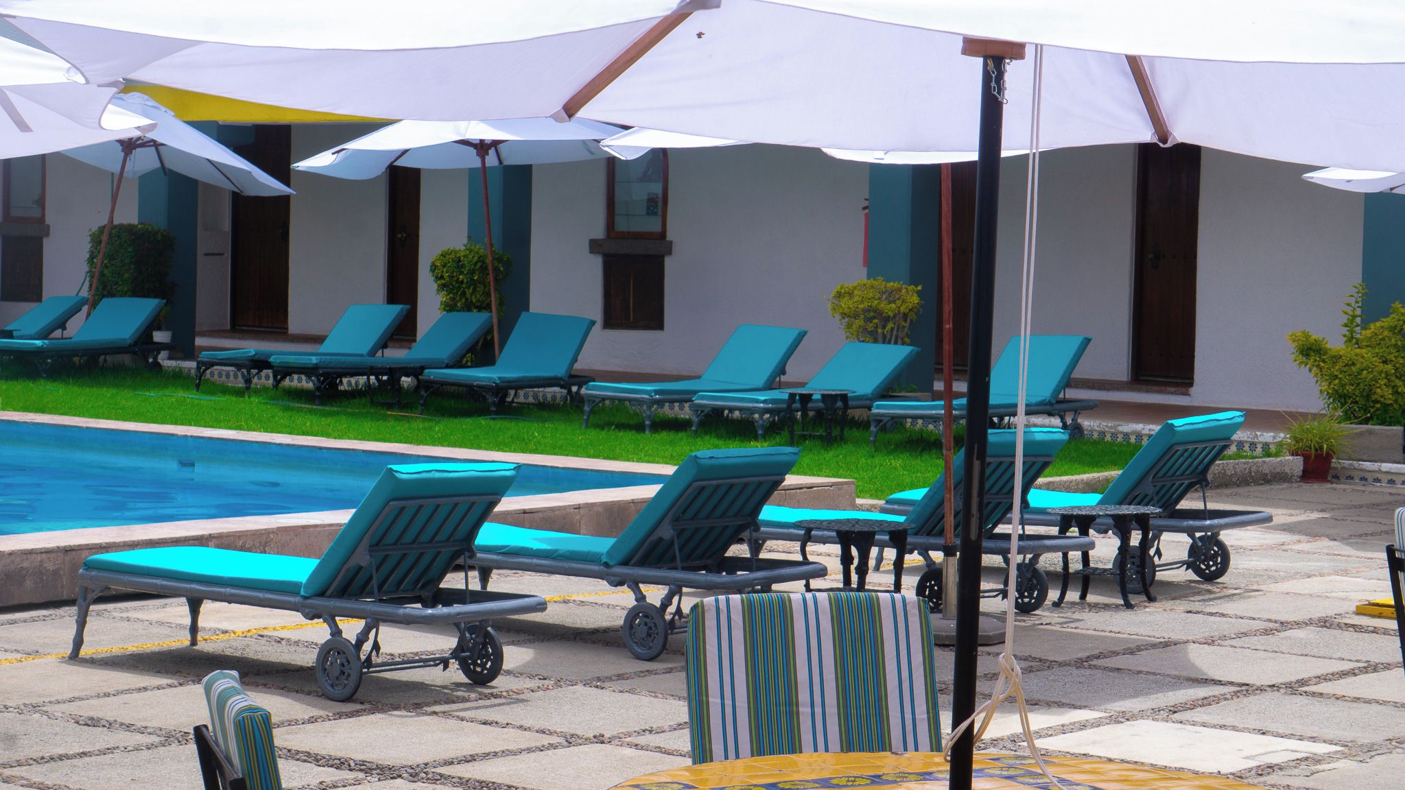 Un área junto a la piscina con sillas de descanso y sombrillas.