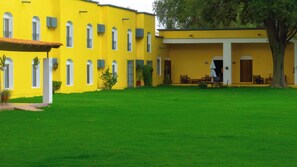 A yellow building with multiple windows and a covered patio area. - Villas Arqueologicas Teotihuacan (Teotihuacan)
