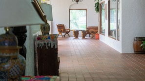 Un couloir avec un sol carrelé, un banc en bois, une chaise et une lampe.
