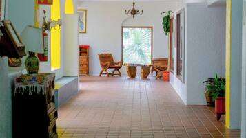 Un pasillo con suelo de baldosas, muebles de madera, un candelabro y una puerta que da al exterior.