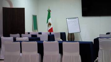 A conference room with tables, chairs, a flag, and a whiteboard.