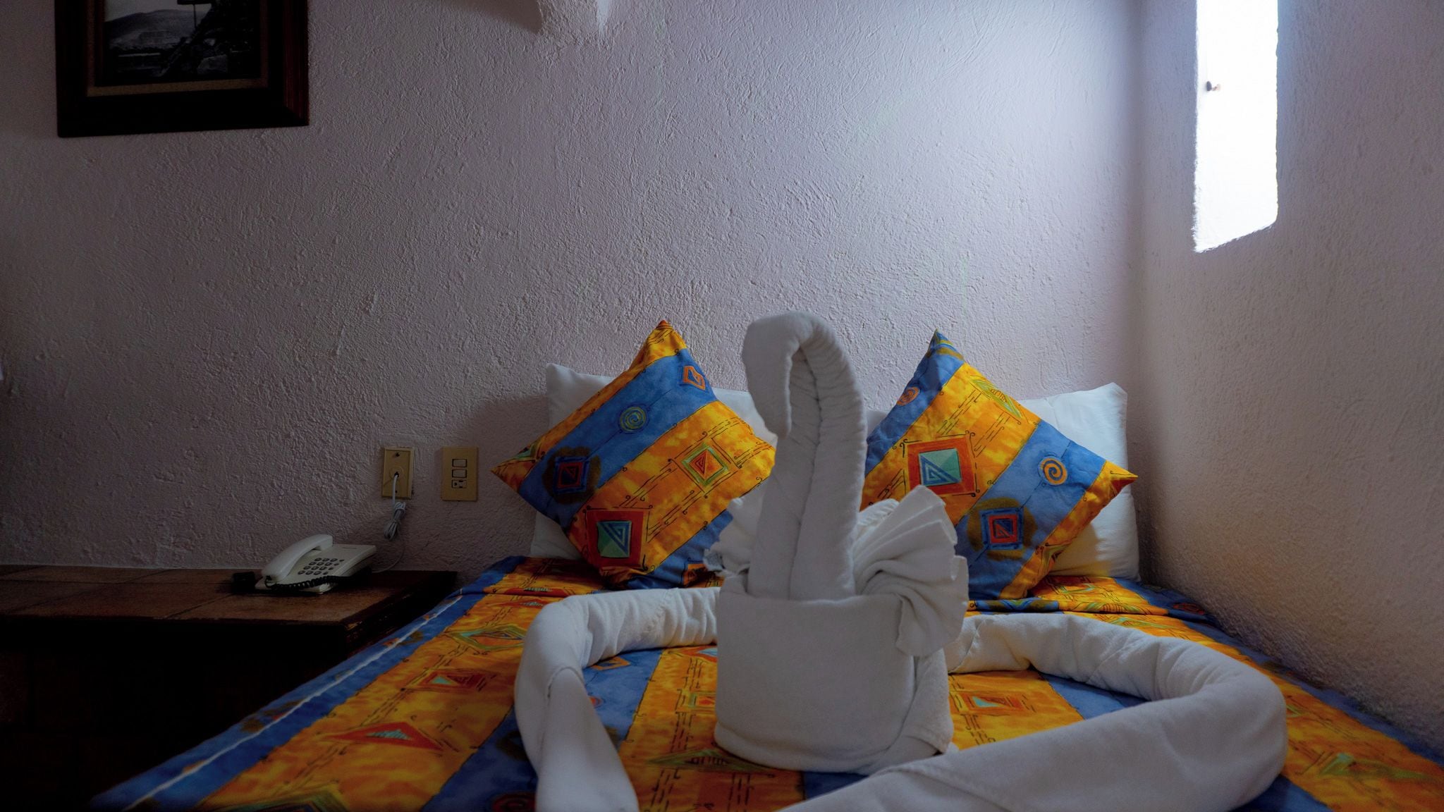 Una habitación de hotel con una cama, un teléfono y una ventana.