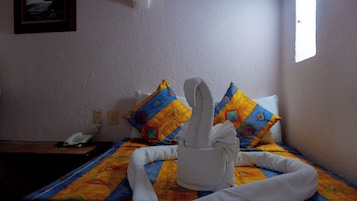 Una habitación de hotel con una cama, un teléfono y una ventana.