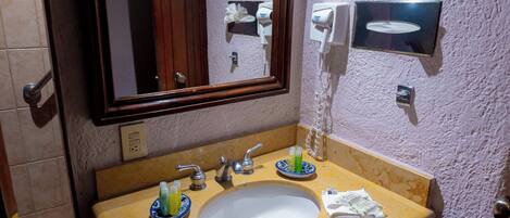 Une salle de bain équipée d’un lavabo, d’un miroir, d’un distributeur de serviettes et d’un distributeur de savon fixé au mur.