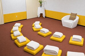 A room with a brown carpet, yellow ottomans, and white towels arranged in a line. - Villas Arqueologicas Teotihuacan (Teotihuacan)