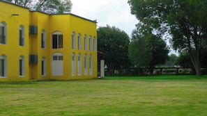 Un bâtiment jaune avec de nombreuses fenêtres et une pelouse verdoyante devant.