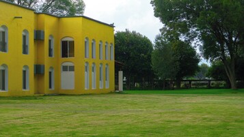Un edificio amarillo con múltiples ventanas y un césped delantero.