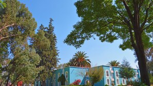 A building with a blue facade, arched windows, and a lawn with trees. - Villas Arqueologicas Teotihuacan (Teotihuacan)