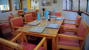 A dining area with wooden tables and chairs, each set with a placemat, a wine glass, and a bottle of wine. - Villas Arqueologicas Teotihuacan (Teotihuacan)