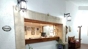 Una zona de recepción con mostrador de madera, certificados enmarcados y un reloj.
