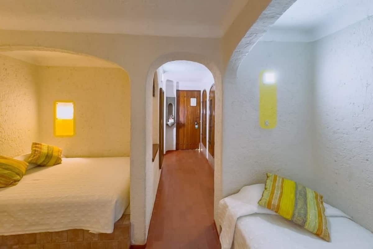 A room with two beds, a hallway, and a door leading to another room.