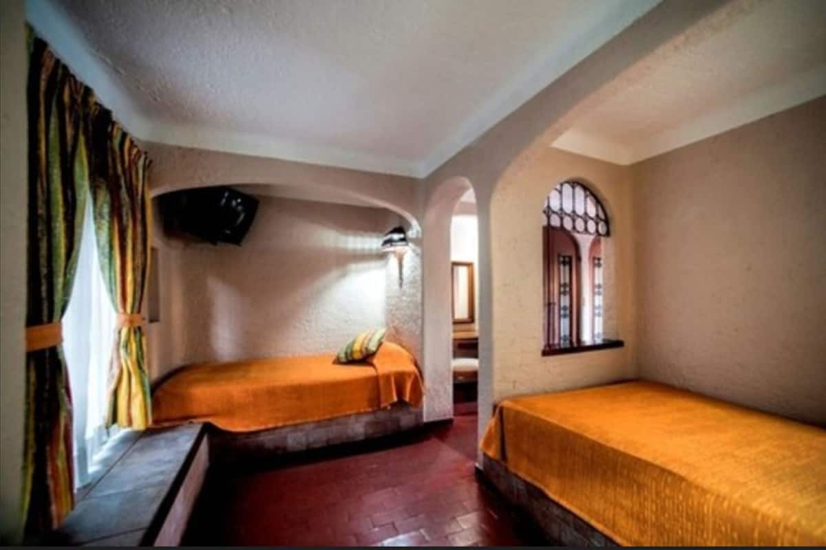 A room with two beds, a television, and a window with a view.