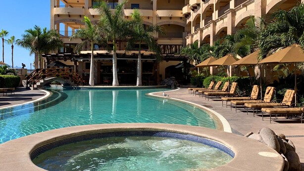 Un hotel con piscina, sillas de descanso y bañera de hidromasaje.