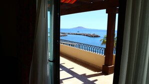 Un balcón con vista al mar, una montaña a lo lejos y un muelle.