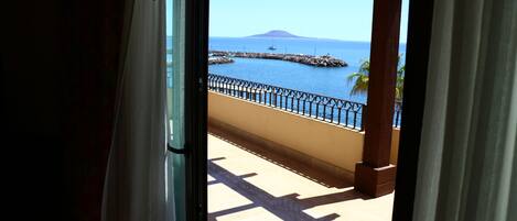 Un balcón con vista al mar, una montaña a lo lejos y un muelle.