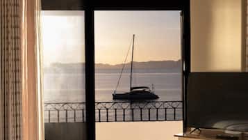 A bedroom with a bed, a desk, and a view of the sea through an open door.