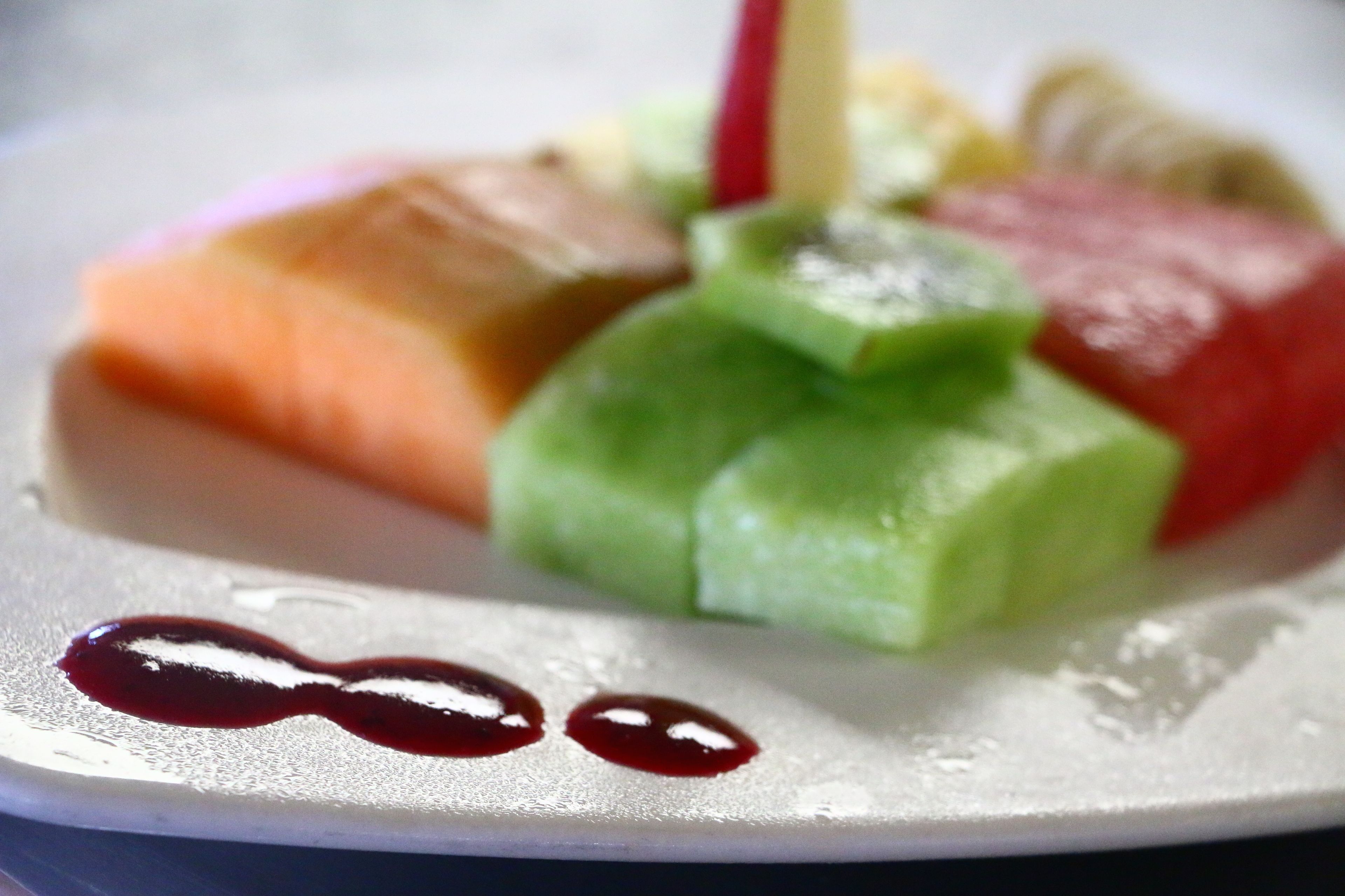 A plate with various food items including salmon, green vegetables, and a red sauce.