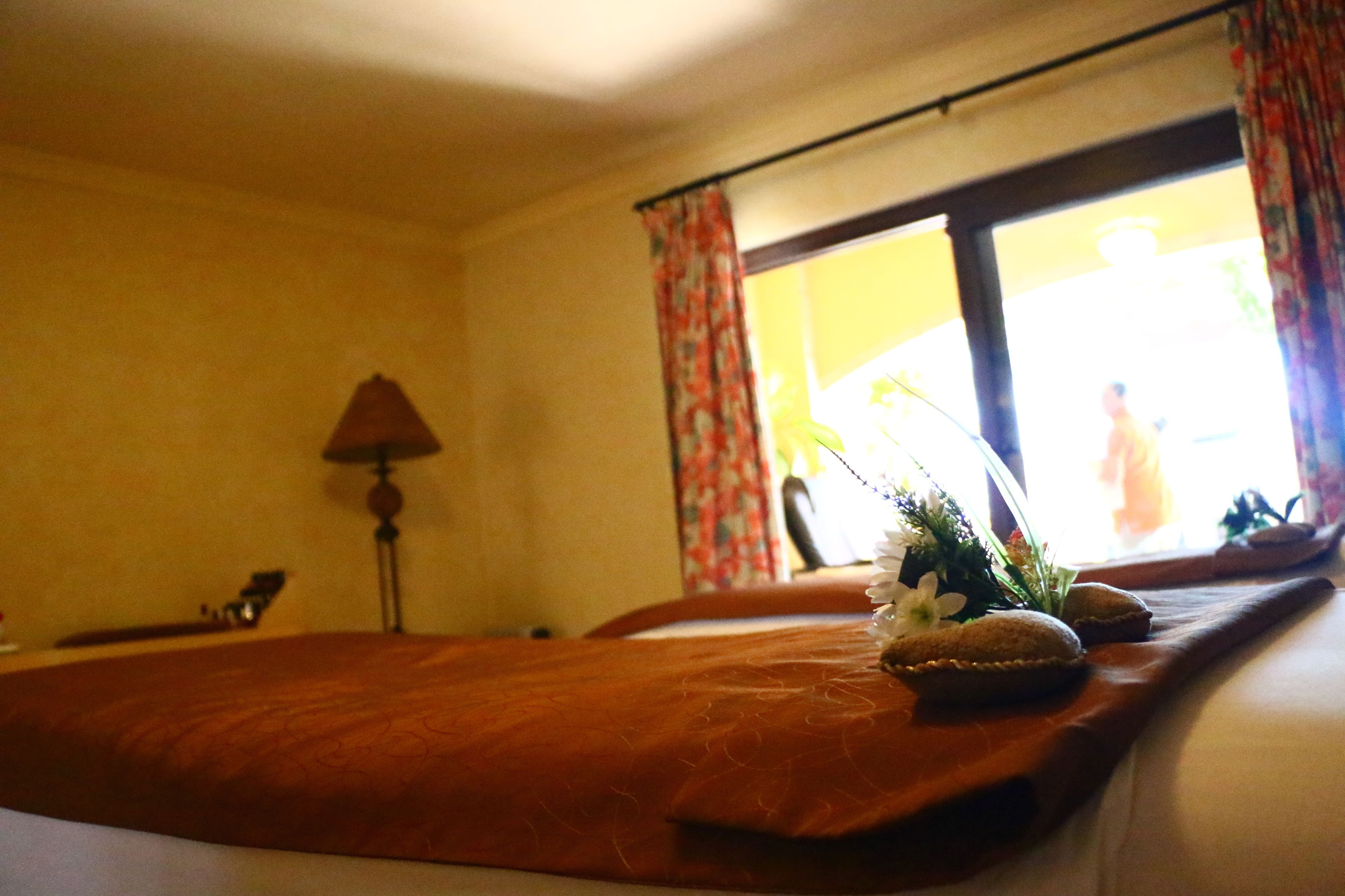 A hotel room with a bed, a lamp, and a window with curtains.