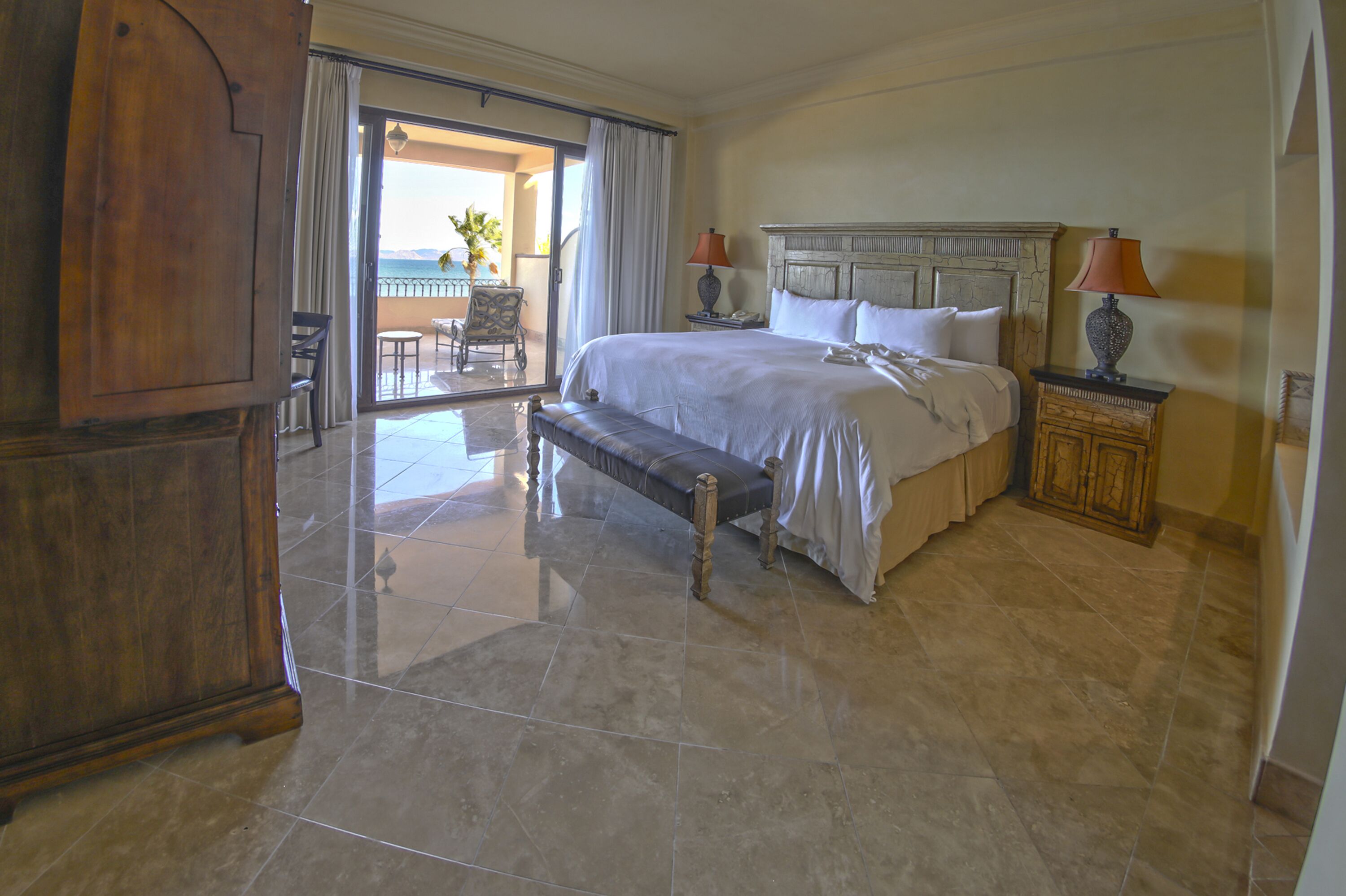 A spacious bedroom with a large bed, a wooden nightstand, and a bench.