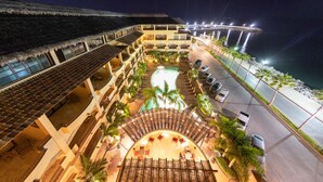 Un hotel con piscina, mobiliario exterior y vista al océano.