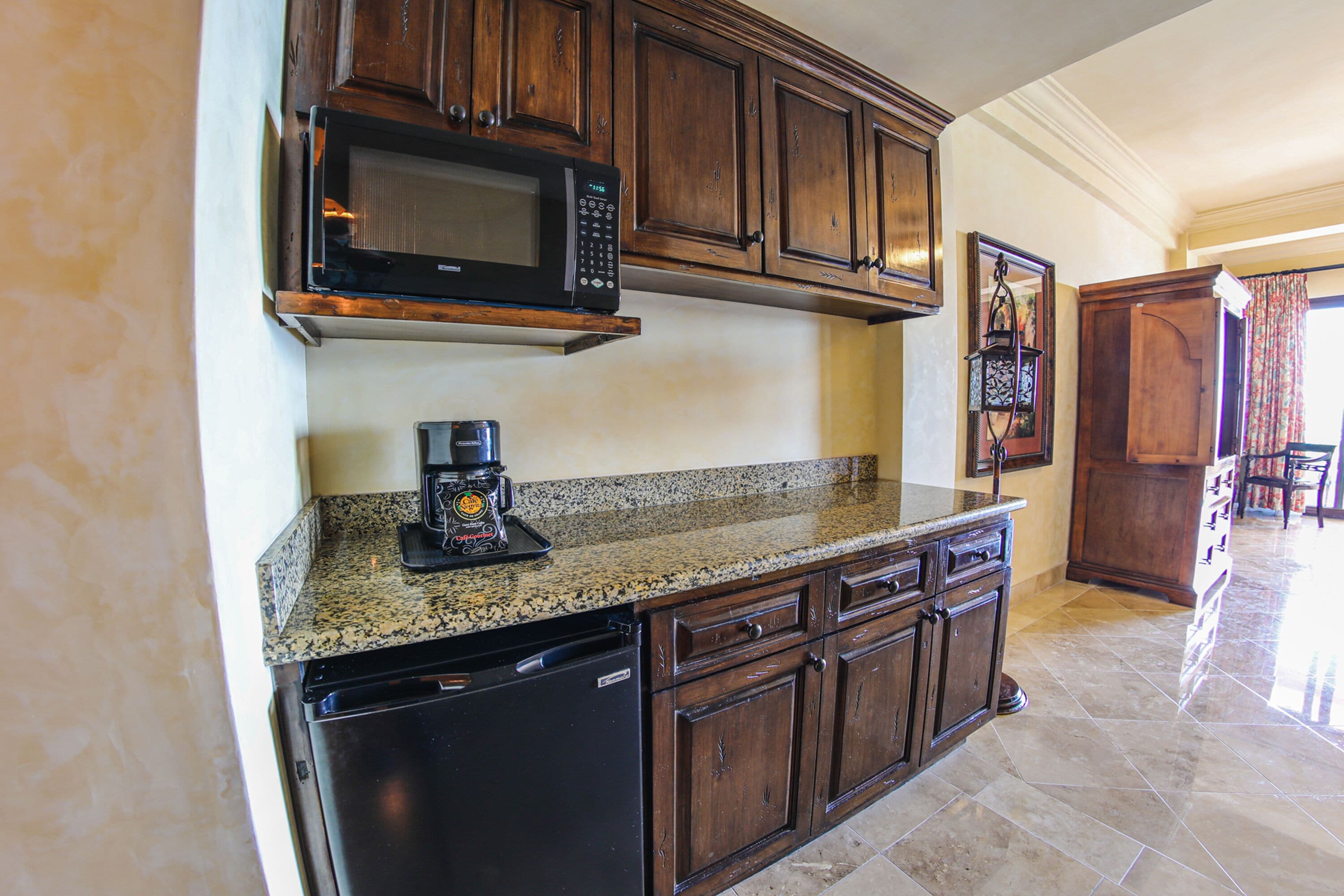 A kitchen with wooden cabinets, a granite countertop, a built-in microwave, and a coffee maker.