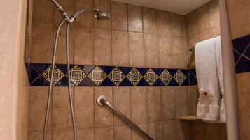 A shower area with a grab bar, a towel rack, and a showerhead.