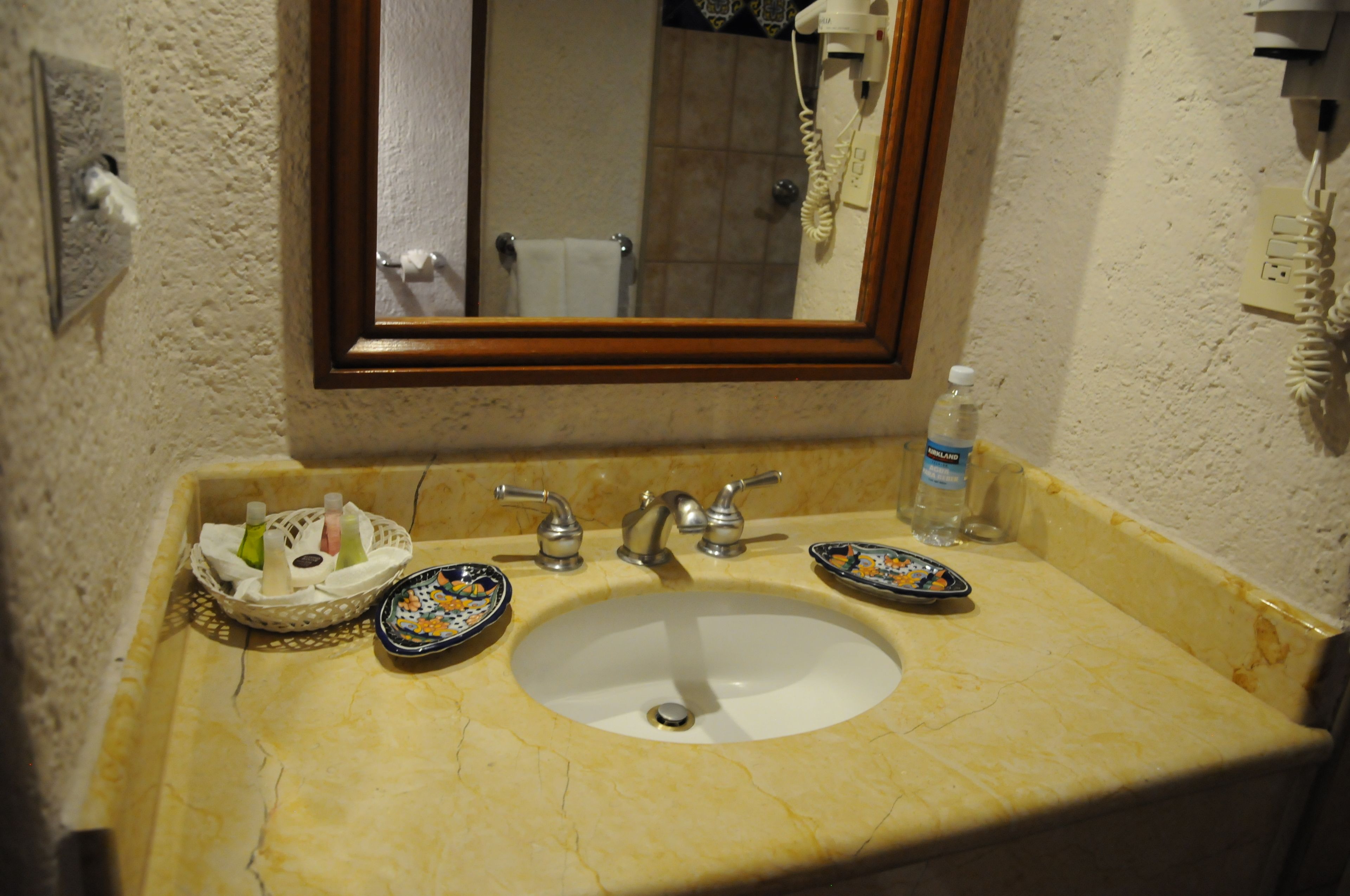 Un lavabo con espejo, dos llaves y una botella de agua.