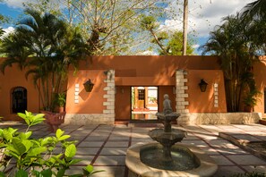 A courtyard with a fountain, palm trees, and a building entrance. - Villas Arqueologicas Chichen Itza (Chichen Itza)