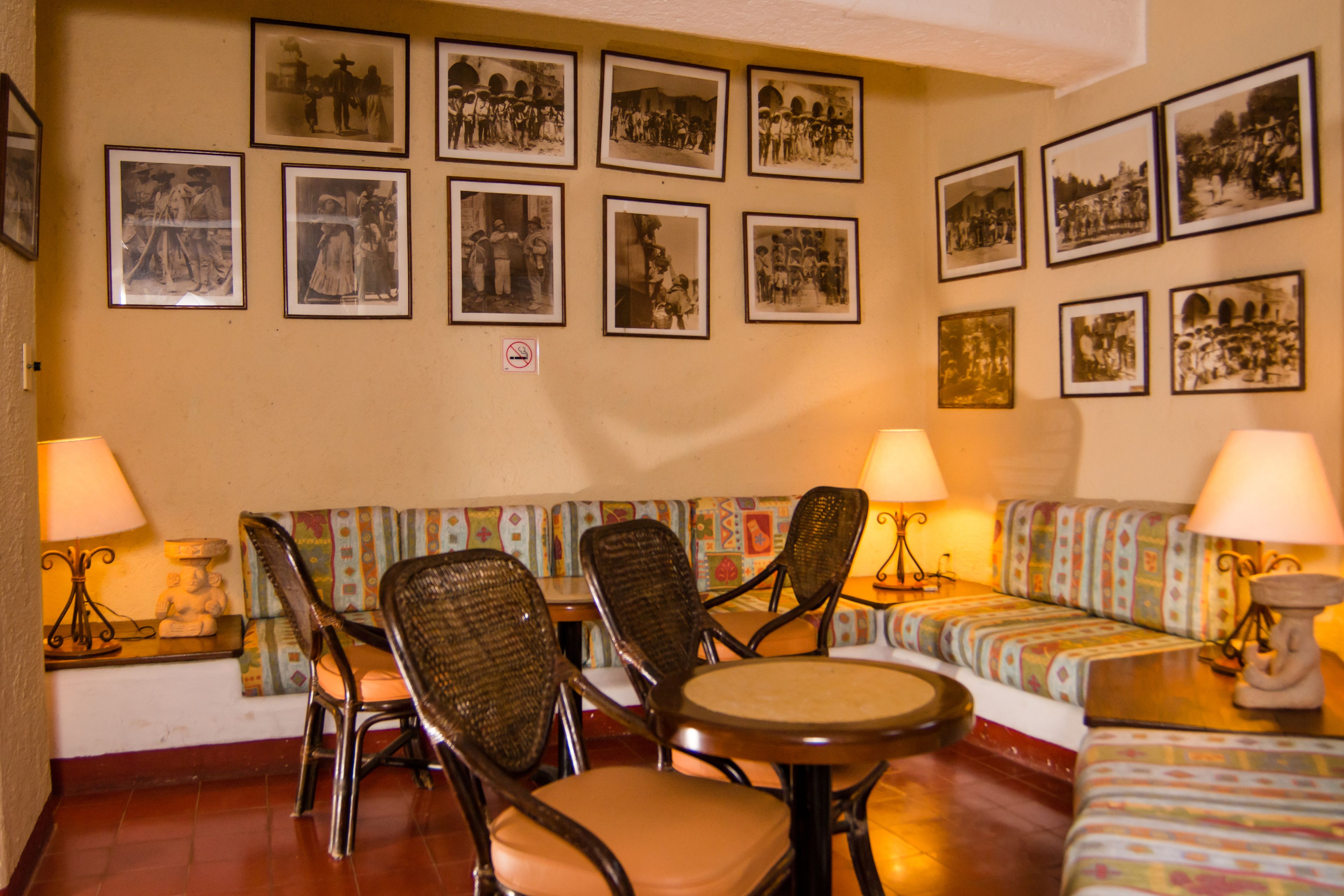 A room with a sofa, chairs, a small table, and wall-mounted picture frames.