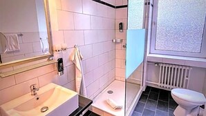 A modern bathroom with a glass-enclosed shower, a white sink, and a toilet.