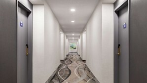 A long, narrow hotel corridor with doors on both sides, each marked with a number. - Days Inn by Wyndham Kingston (Kingston)