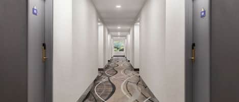 Een lange, smalle hotelgang met deuren aan beide kanten, elk voorzien van een nummer.