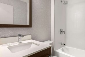 Un baño moderno con lavamanos blanco, un espejo y una ducha.