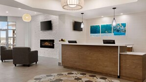 A modern reception area with a wooden reception desk, a fireplace, two sofas, and artwork on the walls. - Days Inn by Wyndham Kingston (Kingston)