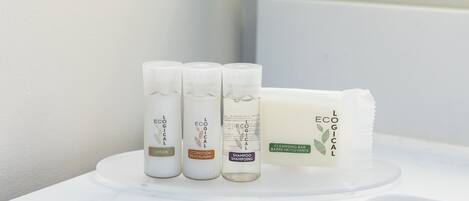 Three bottles of lotion, a bar of cleansing bar, and a shampoo bottle on a white surface.
