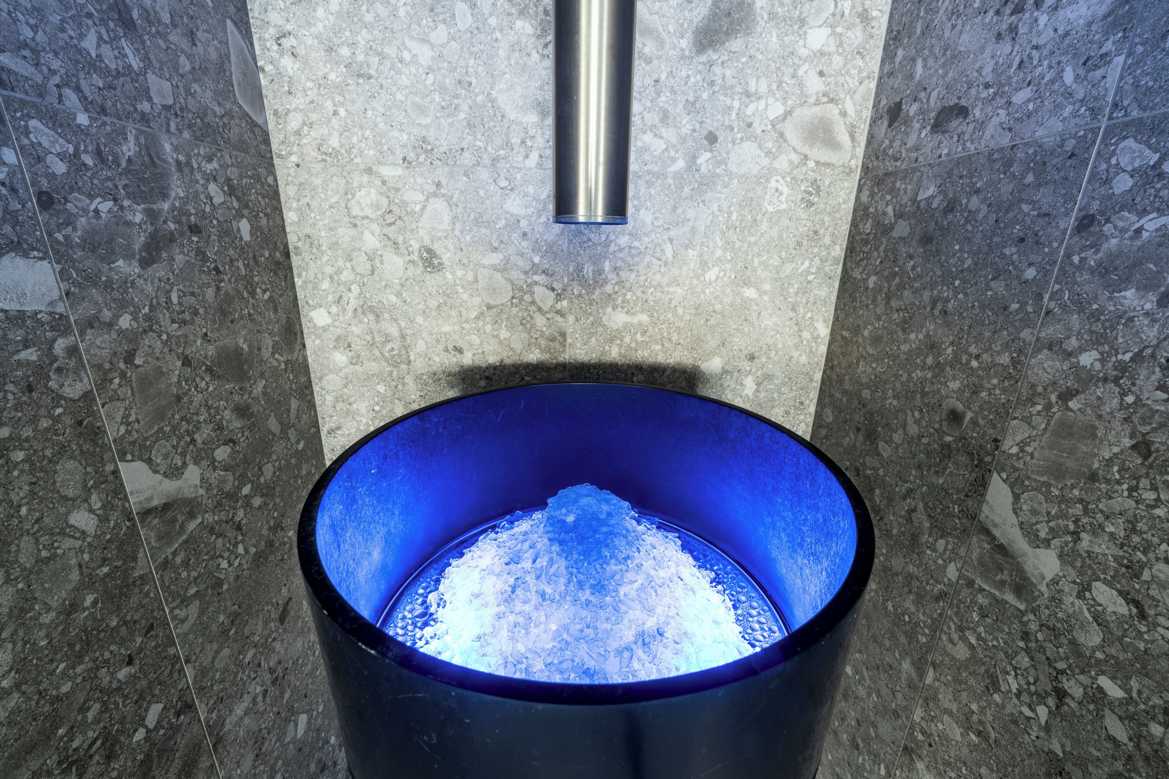 Eine blaue Toilette mit einem Metallrohr darüber.