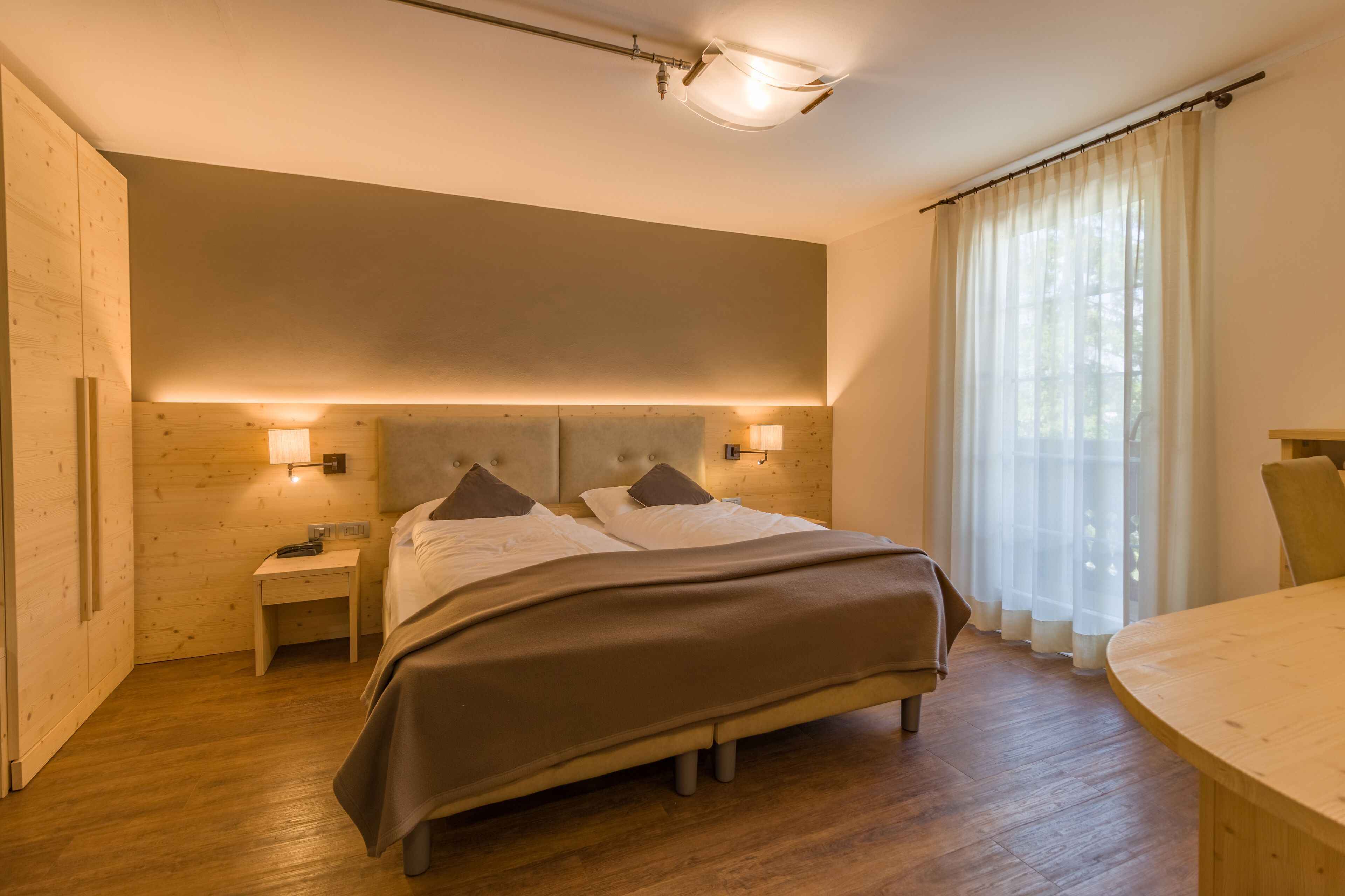 A bedroom with a bed, bedside tables, and a window with curtains.