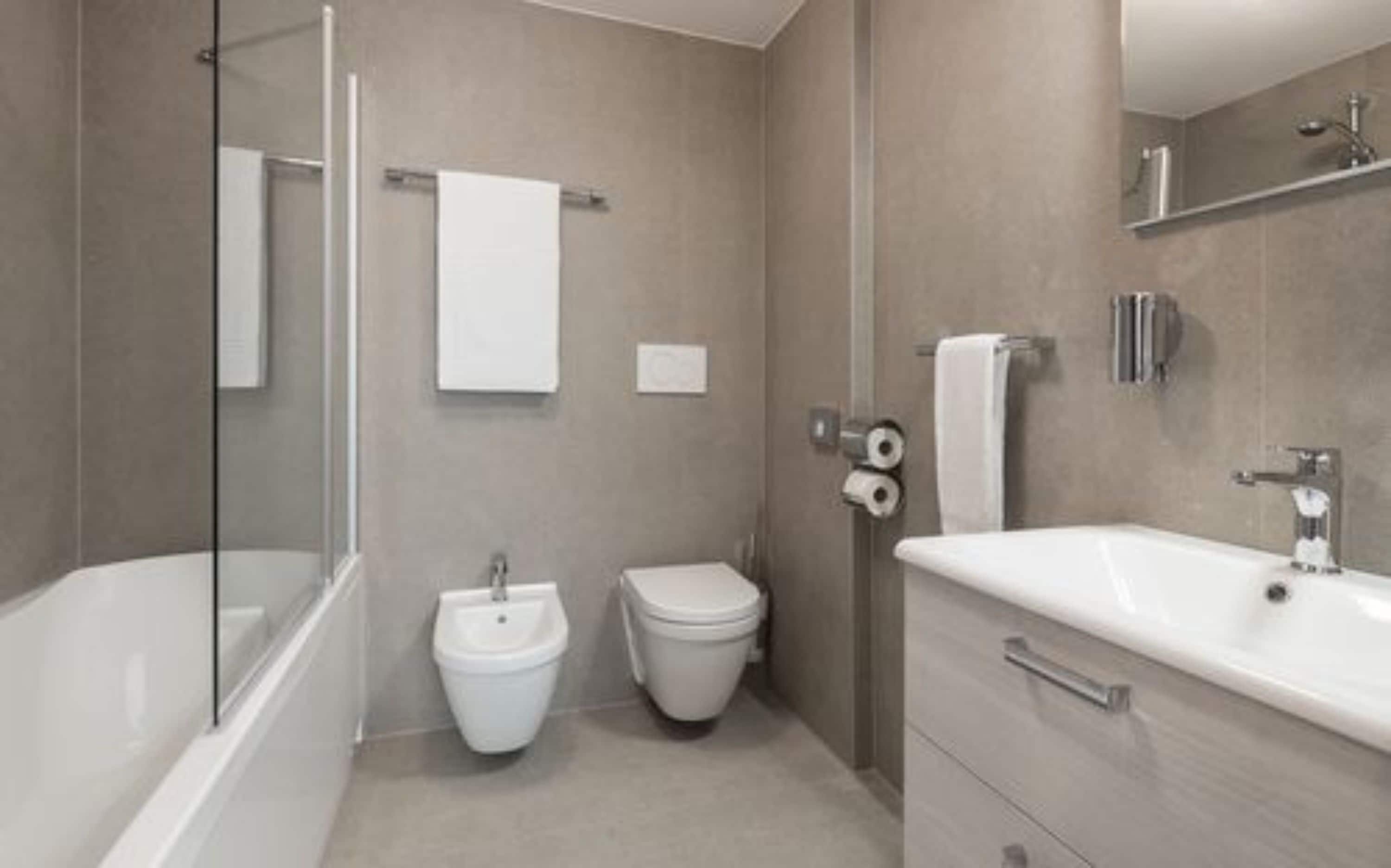 A modern bathroom with a bathtub, toilet, bidet, and sink.