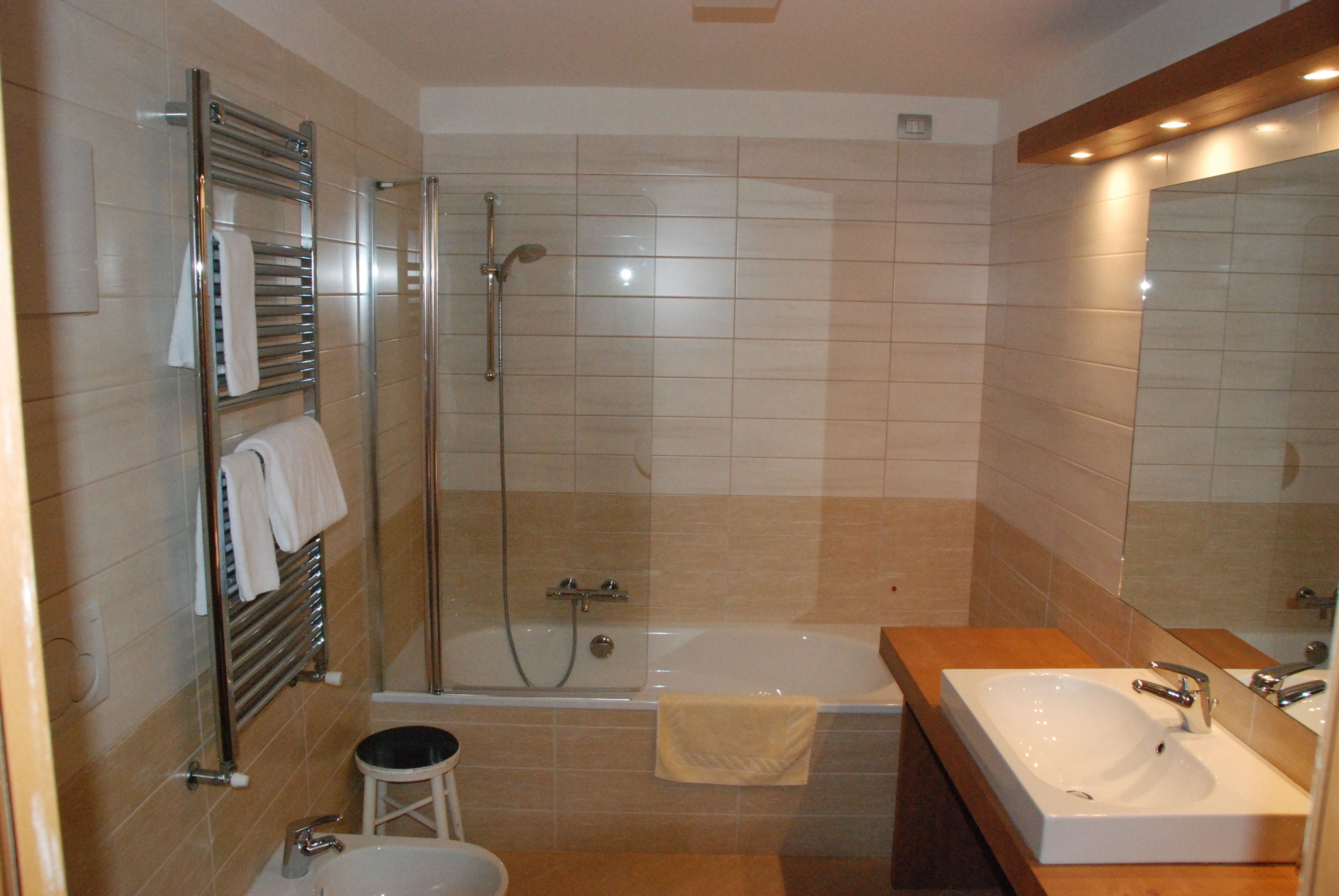 Un baño moderno con ducha envuelta en vidrio, bañera y lavamanos con espejo.