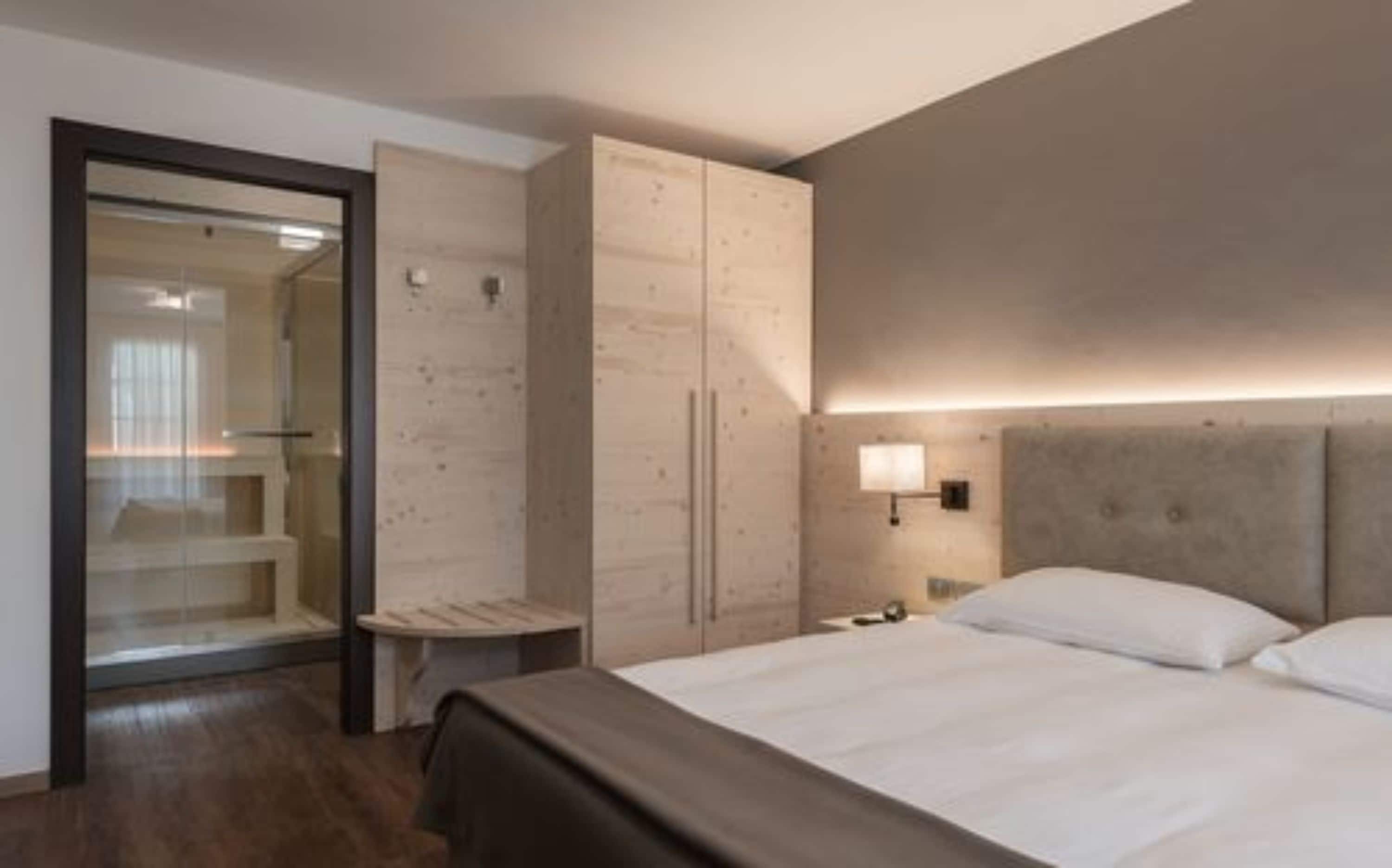Une chambre d’hôtel moderne avec un grand lit, une armoire et un petit coin salon.