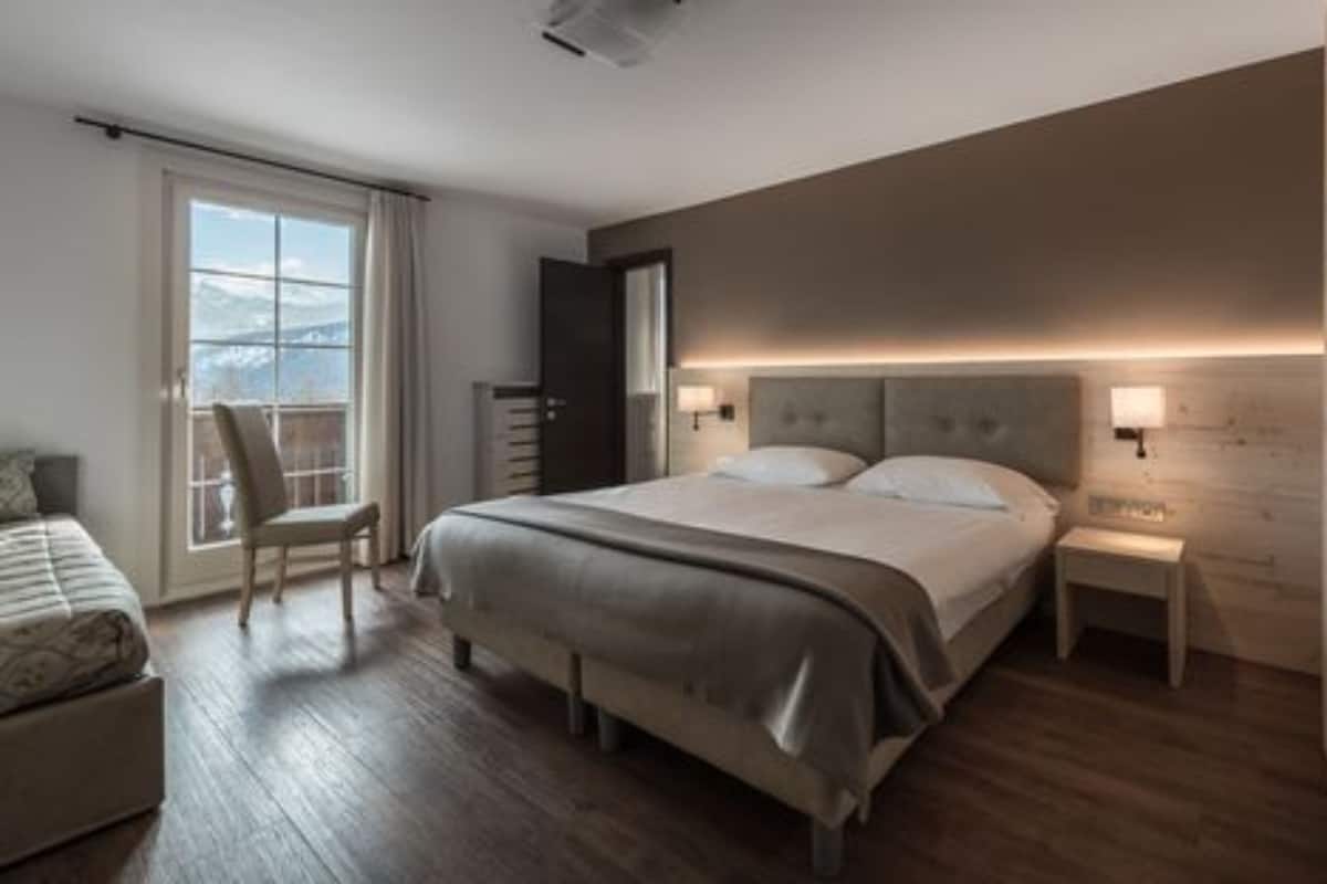 Une chambre à coucher moderne, dotée d’un grand lit, d’une chaise, d’une table de chevet et offrant une vue sur l’extérieur.