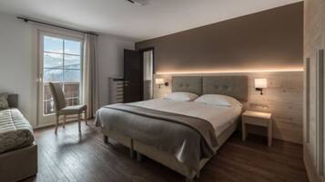 Une chambre à coucher moderne, dotée d’un grand lit, d’une chaise, d’une table de chevet et offrant une vue sur l’extérieur.