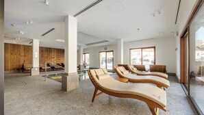 Ein moderner Wellnessbereich mit Liegestühlen, einem Pool, Holzwänden und großen Fenstern.