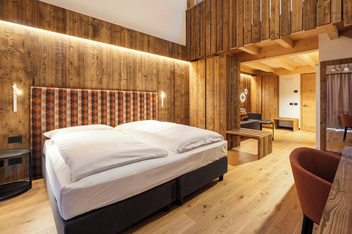 Une chambre moderne avec un grand lit, des murs en bois, un bureau et une chaise.