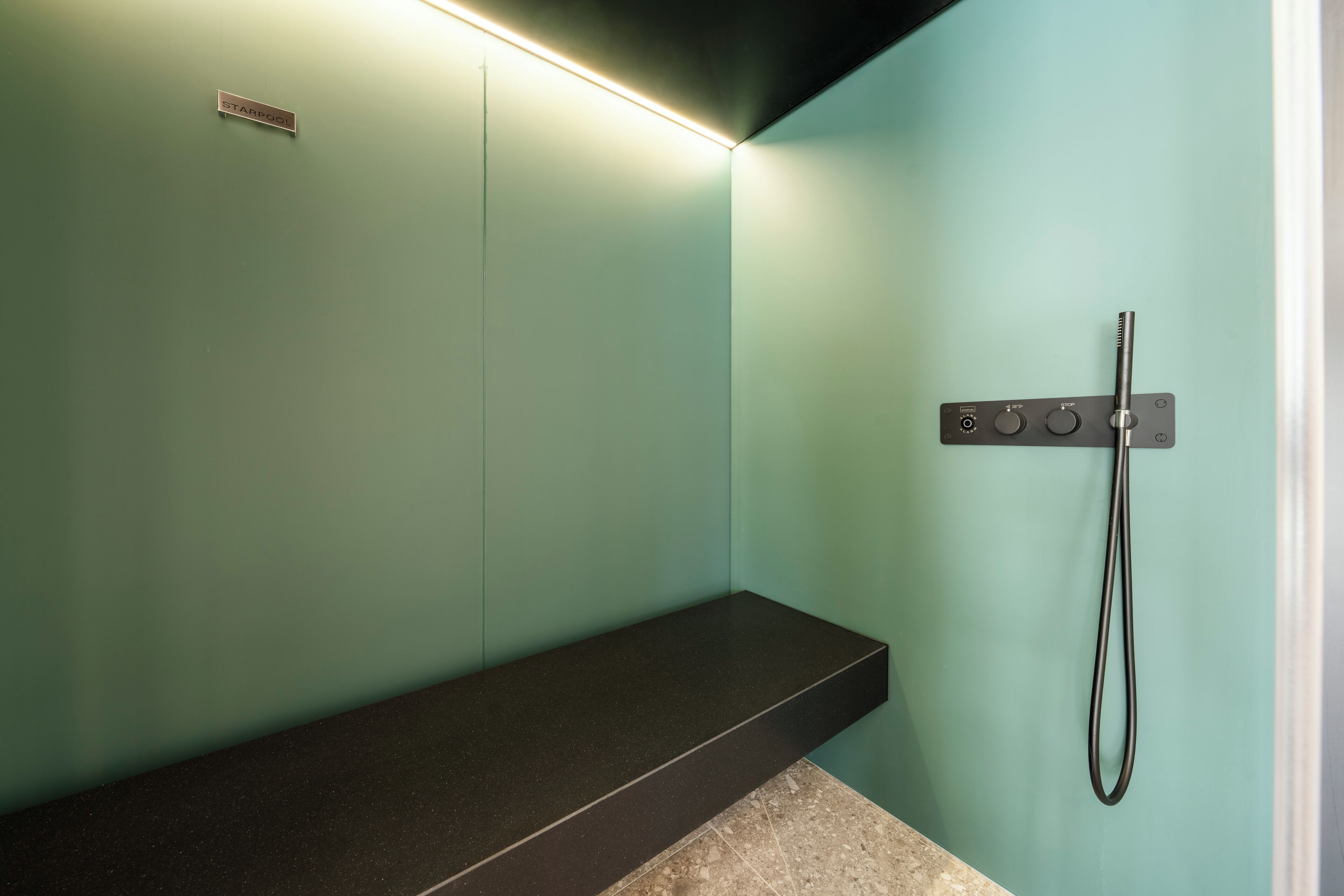 Un bagno con doccia, una panca e una luce a parete.
