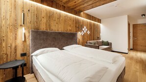 Ein modernes Schlafzimmer mit Holzpaneelen, einem Bett mit weißer Bettwäsche, einem kleinen Tisch und einer Couch.