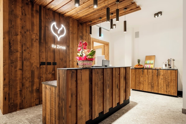 A reception desk with a wooden finish, a neon heart sign, and a floral arrangement.