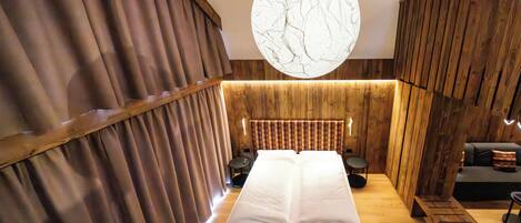 A wooden room with a bed, a round light fixture, and a bench.