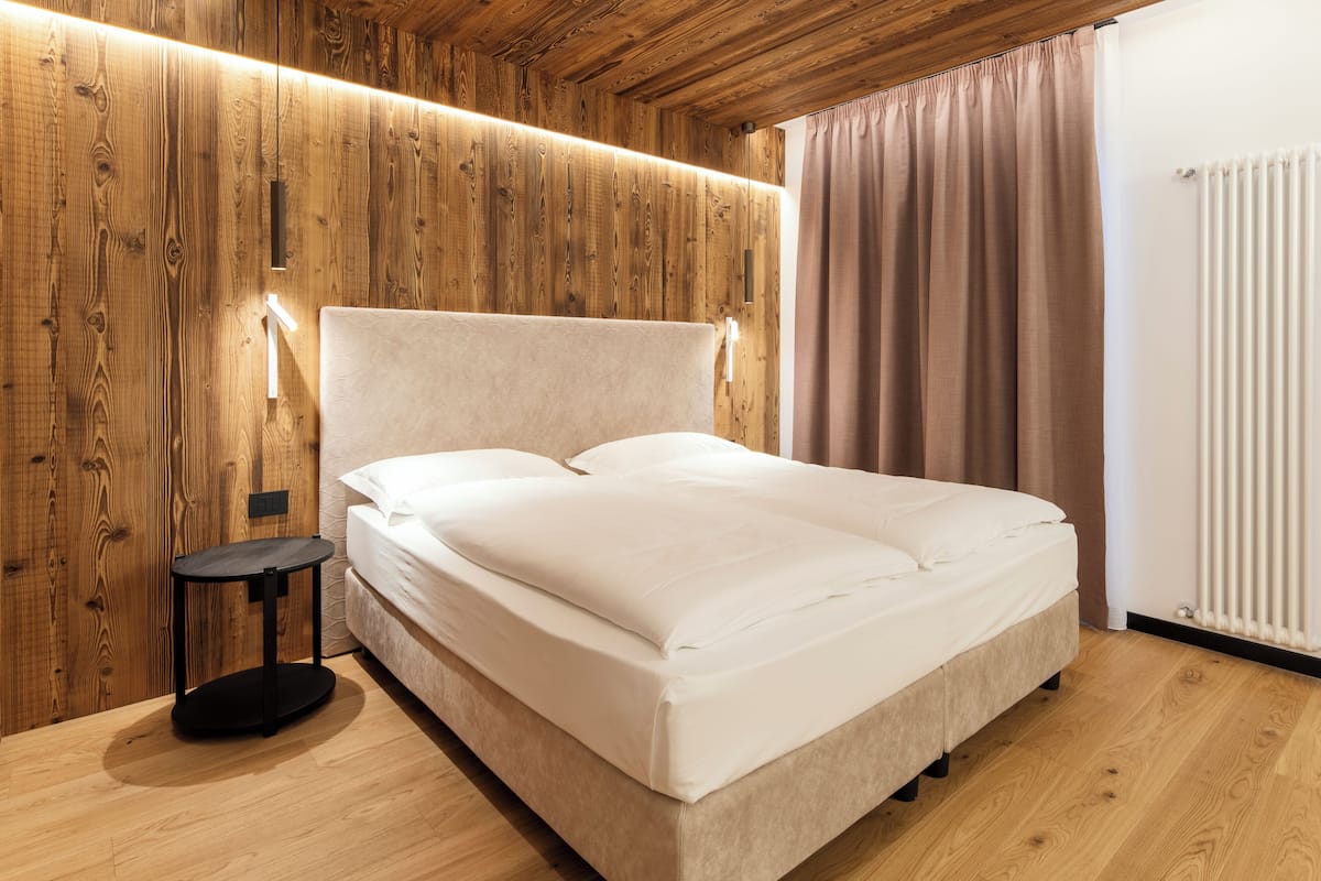 Une chambre avec un mur en bois, un lit, une table de chevet et un radiateur.
